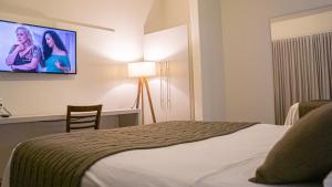 a hotel room with a bed and a flat screen tv at Dom Ravello in Telêmaco Borba