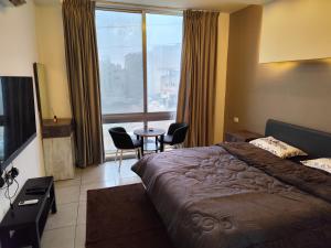 a bedroom with a large bed and a table and chairs at Gentle Breeze Studio 2 in Amman