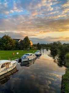 Trois bateaux sont amarrés dans une rivière au coucher du soleil dans l'établissement Leitrim Quay - Riverside Cottage 7, à Leitrim