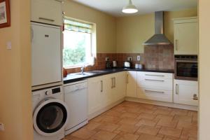 - une cuisine avec des placards blancs et un lave-linge/sèche-linge dans l'établissement Leitrim Quay - Riverside Cottage 7, à Leitrim