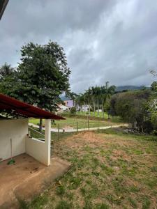 - une vue sur une maison avec un arbre et un champ dans l'établissement Kitnet agradável Alto Caparaó MG, à Caparaó Velho