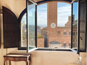een raam met uitzicht op een gebouw met een klok bij Il Campo 8: Piazza del Campo in Siena