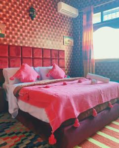 a bedroom with a large bed with a red headboard at Dar Merzouga Meknes in Meknès