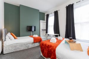 two beds in a room with green walls and windows at Castlereagh guest House in Belfast