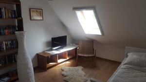 ein Wohnzimmer mit einem Schreibtisch, einem TV und einem Fenster in der Unterkunft Haus Nordsee in Emden