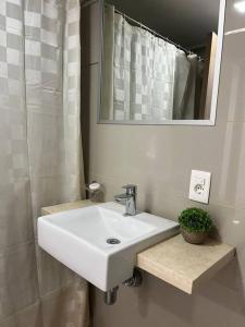 ein Badezimmer mit einem weißen Waschbecken und einem Spiegel in der Unterkunft Solares de Araus, Monoambiente in Colonia del Sacramento