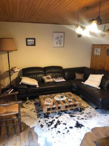 a living room with a black leather couch and a table at Le pigeonnier maison de caractère logement 4 personnes La maisonnette rénovée logement 2 personnes in Floirac