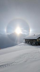 un edificio en la nieve con huellas en la nieve en Alpenpension Elferblick, en Hirschegg