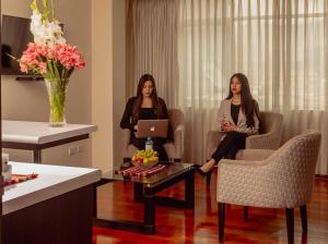 Dos mujeres sentadas en sillas en una habitación con ordenador portátil en Group House Apart Hotel en Cuzco