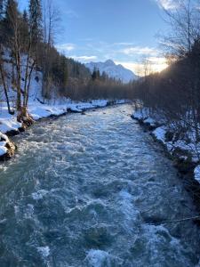 Un río con nieve a sus lados en Alpenpension Elferblick, en Hirschegg