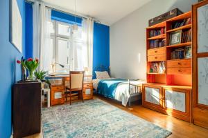 a bedroom with blue walls and a bed and a desk at Botaniczny Pokój in Kraków