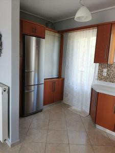 a kitchen with a stainless steel refrigerator and wooden cabinets at Up on the hill in Nafpaktos