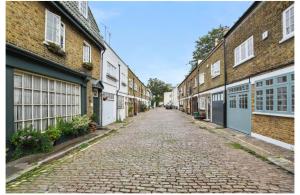 een lege geplaveide straat tussen twee bakstenen gebouwen bij Edgware Road Apartment in Londen