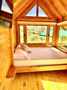 Ce lit se trouve dans une chambre en bois dotée d'une grande fenêtre. dans l'établissement Cabaña de ensueño: 9 min centro, à Chiquinquirá