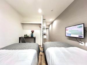 a hospital room with two beds and a flat screen tv at ANX Hostel in Tokyo