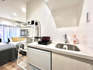 a white kitchen with a sink and a microwave at ANX Hostel in Tokyo