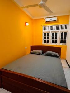 a bedroom with a large bed in a yellow wall at SRI RAGAVAS LAGOON VILLA in Katunayaka