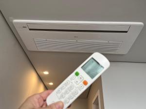 a person holding a remote control in front of a air conditioner at Resort com Piscina Aquecida e Garagem em Xangri-lá in Xangri-lá