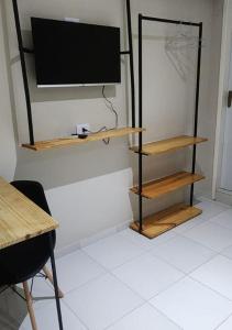 a room with a tv on a wall with wooden shelves at BOB Suítes in Porto De Galinhas