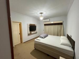 a bedroom with a bed and a flat screen tv at Suíte de Luxo no centro, com hidromassagem e closet in Sinop