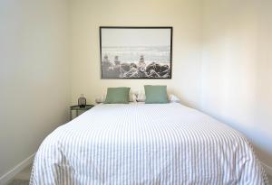 Un dormitorio con una cama blanca con una foto en la pared en Apartamento con vistas al Náutico de San Vicente en O Grove