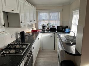 a kitchen with white cabinets and black counter tops at London Tottenham - good for centre and Redwood House-autism in London