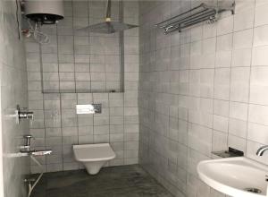 W wyłożonej białymi kafelkami łazience znajduje się toaleta i umywalka. w obiekcie Hostel Nirvana w mieście Udaipur