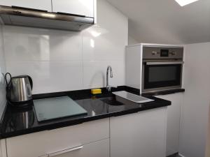 a white kitchen with a sink and a microwave at Central Sesimbra 26 in Sesimbra
