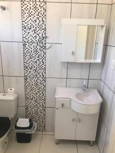 a white bathroom with a sink and a toilet at Casa Água Azul in Machadinho