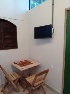 um quarto com duas cadeiras e uma mesa e uma televisão na parede em Pousada Sobre A Rocha em Praia de Araçatiba