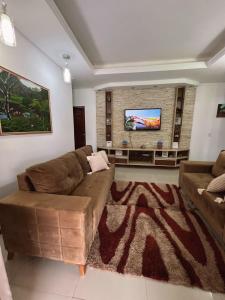 a living room with a couch and a flat screen tv at Casa de Praia em Lagoa do Pau Coruripe in Coruripe