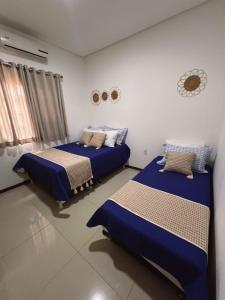 2 Betten in einem Zimmer mit blauer Bettwäsche in der Unterkunft Casa de Praia em Lagoa do Pau Coruripe in Coruripe