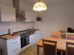 a kitchen with white cabinets and a table and a chandelier at Ferienwohnung Am Homburg Nr 3 in Saarbrücken