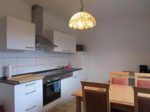 a kitchen with white cabinets and a table and a chandelier at Ferienwohnung Am Homburg Nr 3 in Saarbrücken +12 photos