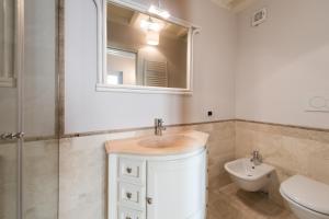 een badkamer met een wastafel, een toilet en een spiegel bij Castel del Mare in San Vincenzo