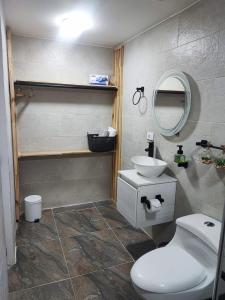 uma casa de banho com um WC branco e um lavatório. em Hotel a resting place 1 AEROPUERTO em Bogotá