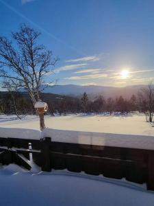 a fence covered in snow with the sun in the background at Koslig hytte ved Grimsdalen in Dovre