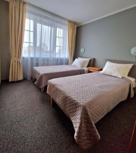 a hotel room with two beds and a window at Hotel Linda - Helvita in Liepāja