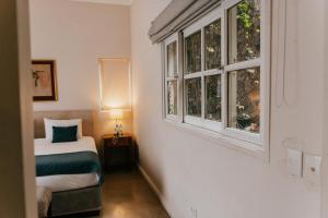 a bedroom with a bed and two windows at BENS L'Hôtel Palermo in Buenos Aires