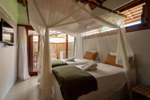 two beds in a room with a canopy bed at Pousada Cajueiro Trancoso in Trancoso