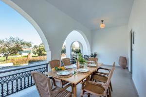 a dining room with a table and chairs on a balcony at Villa INVA Korfu in Kavos