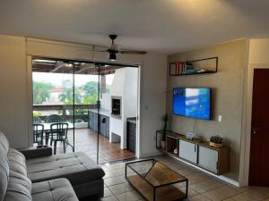 uma sala de estar com um sofá e uma televisão de ecrã plano em Cobertura com Vista para o Mar em Florianópolis