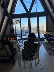 Eine Person sitzt in einem Sessel in einem Raum mit Kamin in der Unterkunft The Sunset Cabin будиночок з Чаном Чан не входить у вартість in Zhuraky