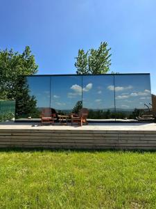 a glass building with two chairs and a table at Perspective Mirror House in Kocaeli