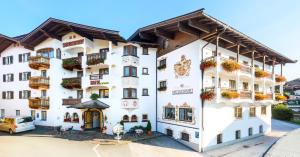 a white building with flower boxes on the balconies at Hotel Metzgerwirt in Kirchberg in Tirol