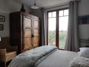 - une chambre avec une grande armoire en bois et une fenêtre dans l'établissement Les Quatre Vents, à Avallon
