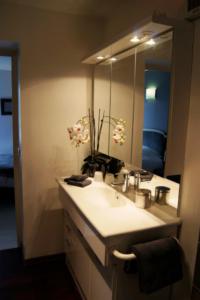 La salle de bains est pourvue d'un lavabo et d'un grand miroir. dans l'établissement Chambres d'Hôtes La Parenthèse, à Wambrechies