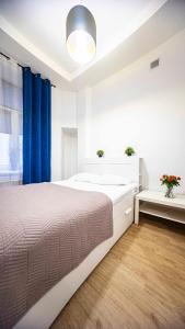 a white bedroom with a large bed and a blue curtain at Spacious Apartment with 3 meter ceilings, Powiśle, The Old Town in Warsaw