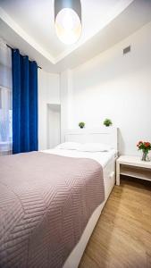 a white bedroom with a large bed and a blue curtain at Spacious Apartment with 3 meter ceilings, Powiśle, The Old Town in Warsaw