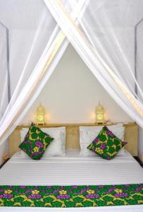 a white bed with two pillows in a tent at Daima Villas in Jambiani